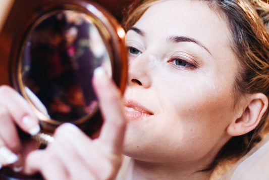 Woman Looking At Her Beautiful Skin in a mirror