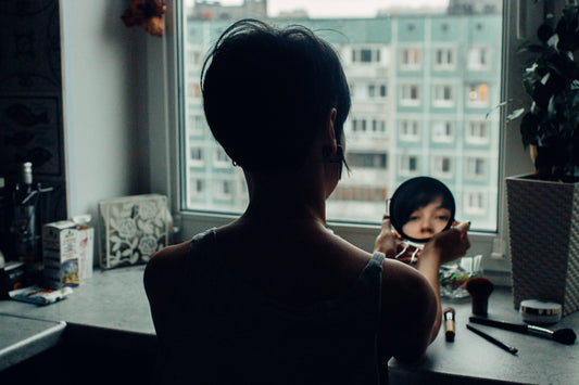 Woman with Melasma Hyperpigmentation looking into a hand mirror
